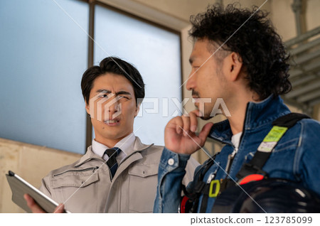 A man in work clothes looking at a drawing and having a meeting 123785099