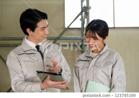 Men and women in work clothes looking at drawings and having a meeting Men and women in work clothes looking at drawings and having a meeting 123785100