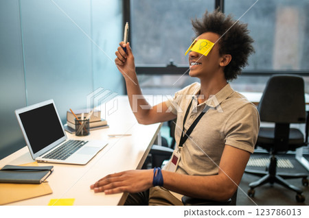 Man with yellow notes on face having fun in office 123786013