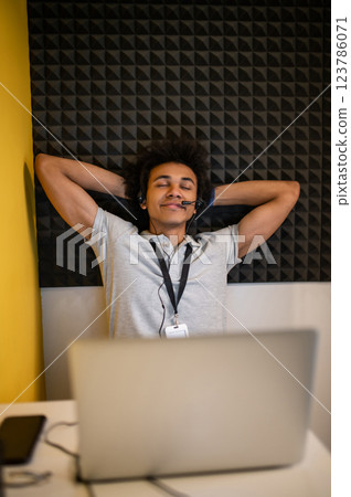 Young curly-haired man stretching and feeling tired after a long work Young curly-haired man stretching and feeling tired after a long work 123786071