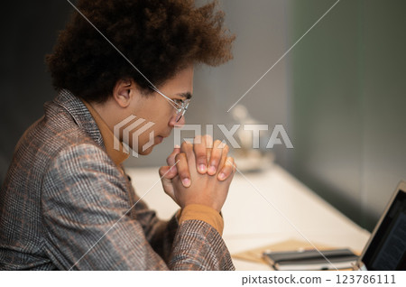 Businessman sitting at the laptop with a serious look and thinking Businessman sitting at the laptop with a serious look and thinking 123786111