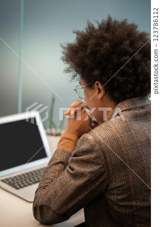 Businessman sitting at the laptop with a serious look and thinking Businessman sitting at the laptop with a serious look and thinking 123786112