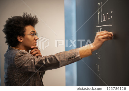 Curly-haired businessman doing business planning and writing on the board Curly-haired businessman doing business planning and writing on the board 123786126