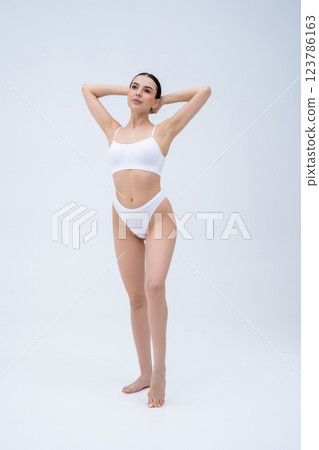 Slim beautiful young woman in white lingerie in a white background Slim beautiful young woman in white lingerie in a white background 123786163