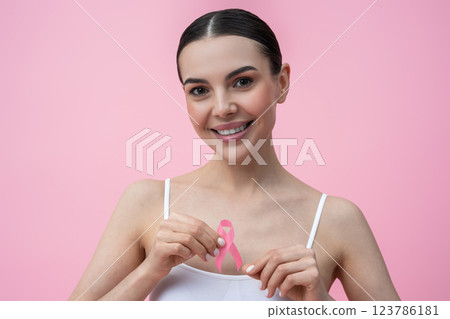 Waist up of a smiling young woman with a pink ribbon in hands 123786181