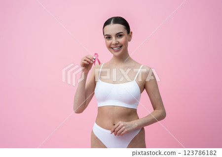 Waist up of a smiling young woman with a pink ribbon in hands 123786182
