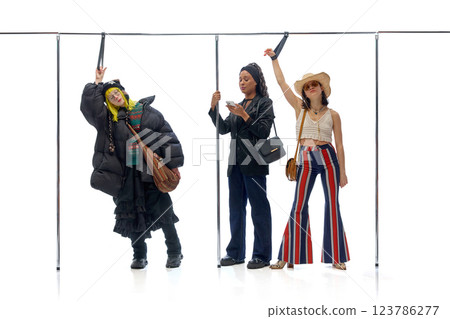 Three individuals in distinct outfits standing together in public setting against white background. Concept of individuality 123786277