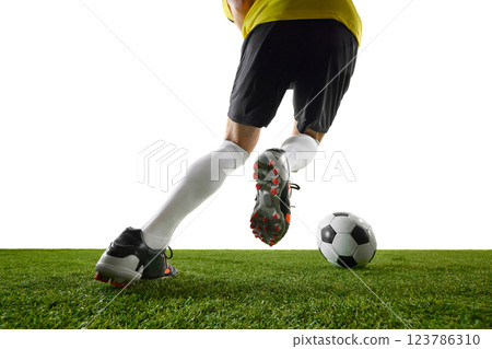 Low angle view of man, soccer player in professional boots and uniform in motion on stadium, dribbling ball, playing against white background. 123786310