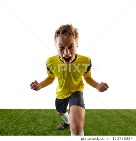 Close-up image of young man, soccer player shouting with intensity, fists clenched, running forward, expressing raw emotions after major play. 123786324