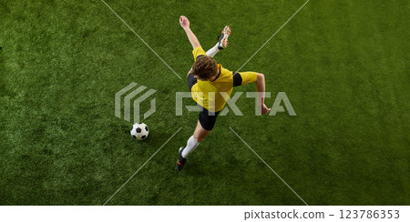 Top view dynamic image of determined young man, soccer player in motion on green stadium, controlling ball, playing. Top view dynamic image of determined young man, soccer player in motion on green stadium, controlling ball, playing. 123786353