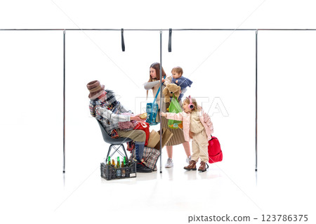 Little girl reaching for bread from homeless man while mother holds baby against white studio background. 123786375
