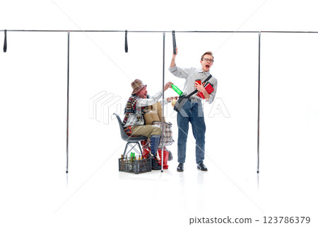 Student reacting in shock as homeless man reaches out with bottle, standing inside imaginary subway against white studio background. 123786379