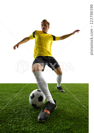 Dynamic low angle view of young man, soccer player controlling ball, stabilizing stance, preparing for next move during match and training session Dynamic low angle view of young man, soccer player controlling ball, stabilizing stance, preparing for next move during match and training session 123786396