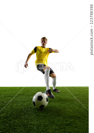 Low-angle view of young man, soccer player controlling ball, maneuvering quickly, positioning himself for strategic play against white background. 123786398