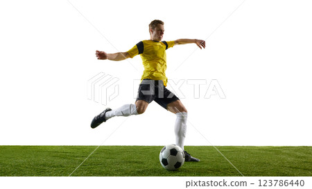 Low angle view of young man, soccer player in motion during game, training, powerfully kicking ball with extended leg against white background. 123786440
