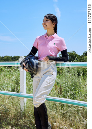 A woman standing with a helmet at a riding club 123787186