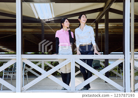 一位女士在騎馬俱樂部的露臺上看著賽馬場 123787193