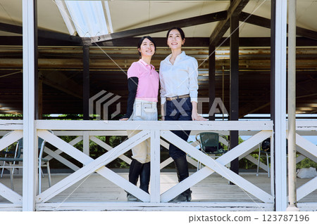 一位女士在騎馬俱樂部的露臺上看著賽馬場 123787196