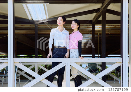 一位女士在騎馬俱樂部的露臺上看著賽馬場 123787199