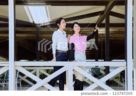 A woman looking at the riding arena from the terrace of a riding club A woman looking at the riding arena from the terrace of a riding club 123787205