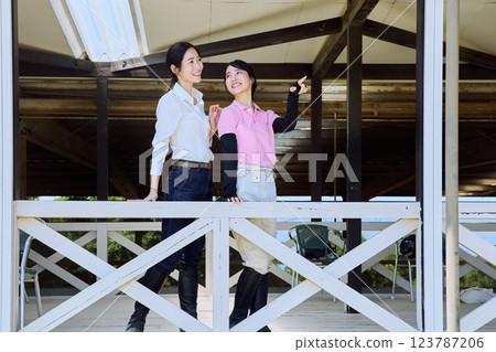 A woman looking at the riding arena from the terrace of a riding club A woman looking at the riding arena from the terrace of a riding club 123787206