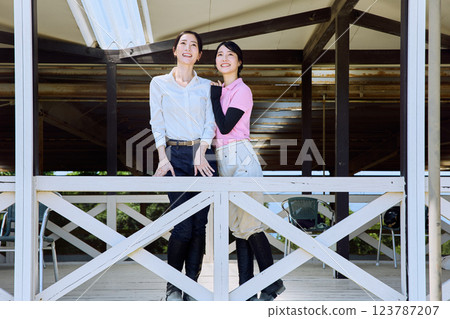 A woman looking at the riding arena from the terrace of a riding club A woman looking at the riding arena from the terrace of a riding club 123787207