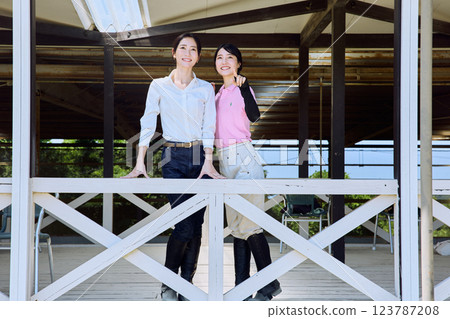 一位女士在騎馬俱樂部的露臺上看著賽馬場 123787208