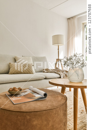 A stylish and cozy modern living room featuring neutral tones, a circular coffee table, and elegant decor elements like flowers and cushions. A stylish and cozy modern living room featuring neutral tones, a circular coffee table, and elegant decor elements like flowers and cushions. 123787688