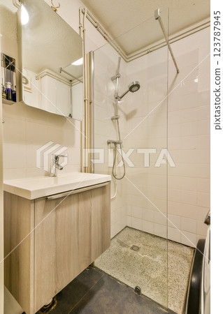 A sleek and minimalistic bathroom featuring a glass shower enclosure, modern sink, and clean tiles, creating a spacious and contemporary appearance. A sleek and minimalistic bathroom featuring a glass shower enclosure, modern sink, and clean tiles, creating a spacious and contemporary appearance. 123787945