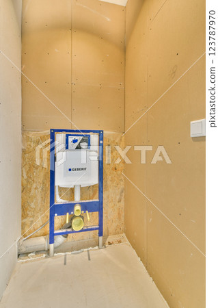 A partially finished bathroom showcasing bare walls, plumbing fixtures, and construction materials, highlighting renovation work in progress. 123787970