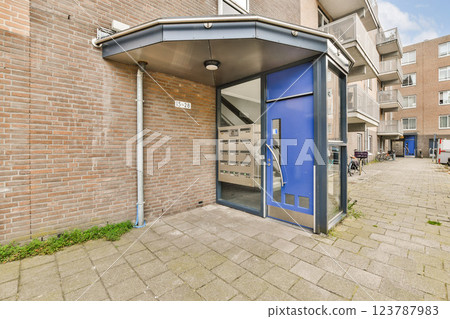A contemporary entrance to an apartment building featuring mailboxes, sleek architecture, and a pedestrian-friendly layout. The design emphasizes functionality and aesthetics. 123787983