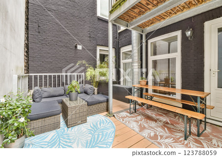 A stylish urban patio featuring a cozy seating area, greenery, and a wooden dining table, creating a perfect outdoor retreat in a contemporary setting. A stylish urban patio featuring a cozy seating area, greenery, and a wooden dining table, creating a perfect outdoor retreat in a contemporary setting. 123788059