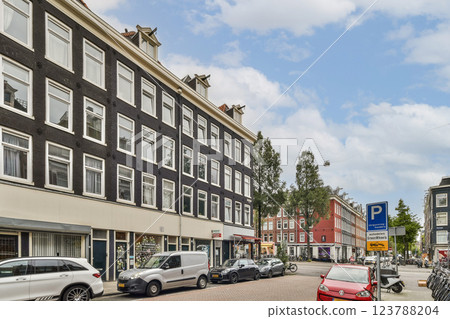 A picturesque street view featuring charming buildings, greenery, and urban life in Amsterdam. The combination of architecture and nature creates a lively atmosphere. 123788204