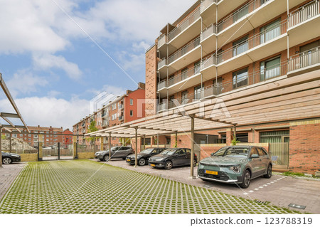 A contemporary residential complex featuring multiple floors adorned with balconies. The parking area is well-organized with spacious spaces visible in the foreground. 123788319
