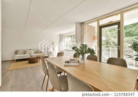 A stylish and cozy living room featuring modern furniture, large windows, and natural light, creating an inviting atmosphere for relaxation and gathering. 123788347