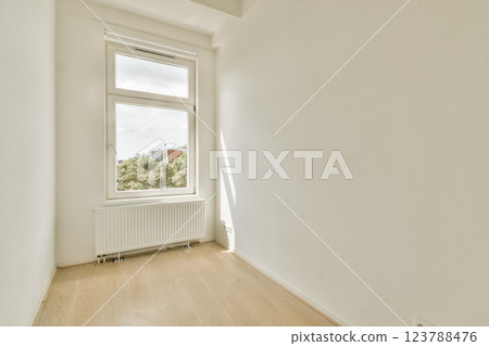 A spacious, empty room featuring a large window that allows sunlight to stream in, highlighting the simplicity of the minimalist design. A spacious, empty room featuring a large window that allows sunlight to stream in, highlighting the simplicity of the minimalist design. 123788476