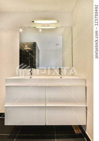 Sleek and contemporary bathroom featuring a double sink vanity, large mirror, and modern fixtures. The design emphasizes cleanliness and simplicity. Sleek and contemporary bathroom featuring a double sink vanity, large mirror, and modern fixtures. The design emphasizes cleanliness and simplicity. 123788492