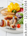 Grilled sausages with vegetables and herbs on a light background 123789364