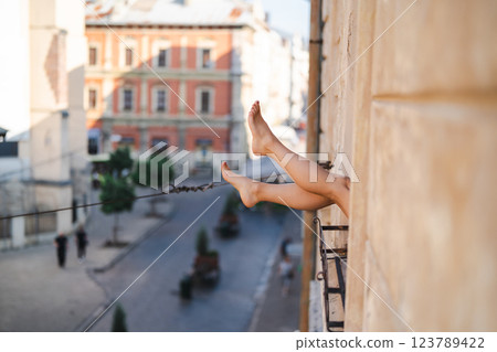 Close-up of female legs with red shoes of high heels. The woman is raising her feet through the window 123789422
