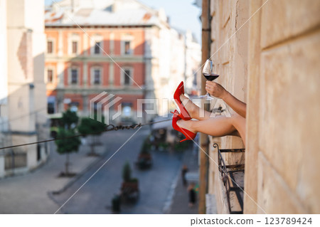 Close-up of female legs with red shoes of high heels. The woman is raising her feet through the window Close-up of female legs with red shoes of high heels. The woman is raising her feet through the window 123789424