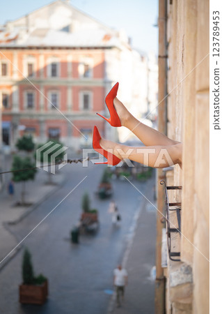 Close-up of female legs with red shoes of high heels. The woman is raising her feet through the window Close-up of female legs with red shoes of high heels. The woman is raising her feet through the window 123789453