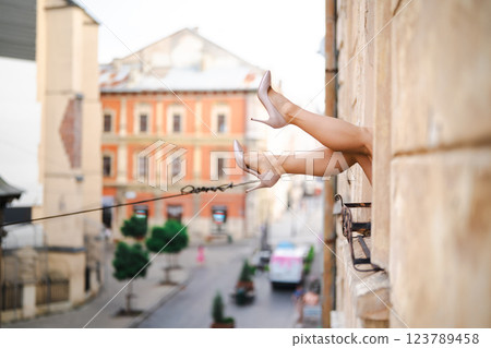 Close-up of female legs with red shoes of high heels. The woman is raising her feet through the window Close-up of female legs with red shoes of high heels. The woman is raising her feet through the window 123789458