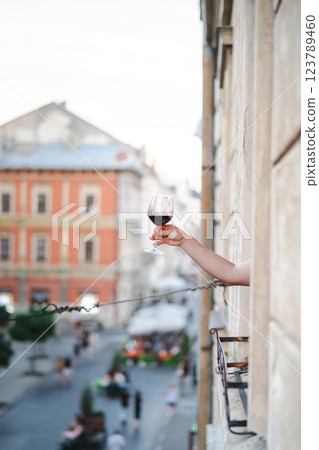 Young woman with glass of red wine on the balcony in the city Young woman with glass of red wine on the balcony in the city 123789460