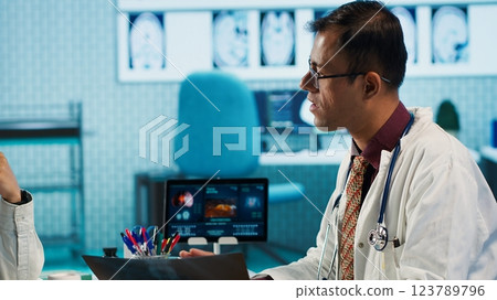 Physician meeting with a patient to discuss medical test results in a cabinet, using advanced diagnostic tools to interpret x ray scans, demonstrating a professional healthcare approach. Camera A. 123789796