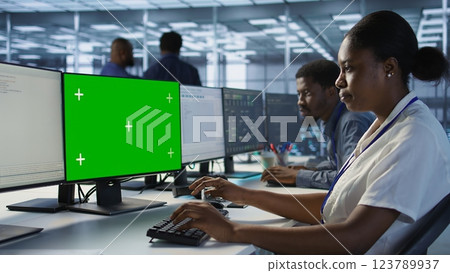 Software developer in server farm ensuring data remains shielded from potential threats using mockup PC. IT expert safeguarding data center against hackers with green screen computer, camera A 123789937