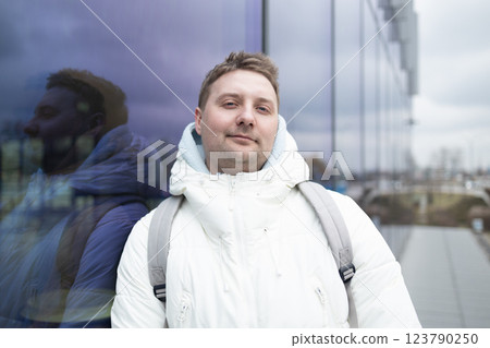 Portrait of Caucasian smiling bearded man with backpack, looking at camera aganist airport terminal building in the winter city. Lifestyle, city life concept Portrait of Caucasian smiling bearded man with backpack, looking at camera aganist airport terminal building in the winter city. Lifestyle, city life concept 123790250
