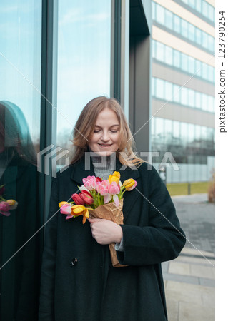 Happy International Women's Day Concept. Beautiful happy Caucasian woman smelling bunch of tulips with closed eyes 123790254