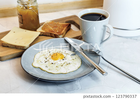 Breakfast served on the kitchen table with a fried egg on a plate and fresh bread and coffee Breakfast served on the kitchen table with a fried egg on a plate and fresh bread and coffee 123790337