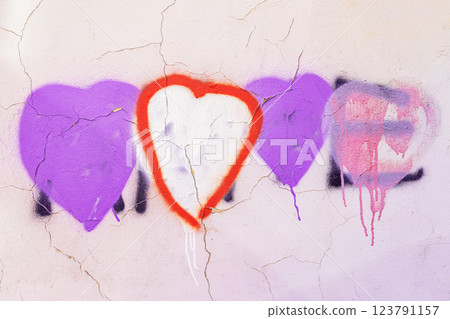 Graffiti hearts painted on a cracked white wall with vibrant red and purple tones. Textured surface, peeling paint create, urban background. Love, passion, urban culture concept Graffiti hearts painted on a cracked white wall with vibrant red and purple tones. Textured surface, peeling paint create, urban background. Love, passion, urban culture concept 123791157