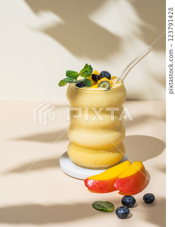 Smoothie with mango, banana and blueberry in a glass on a beige background with slice of fruits  123791428